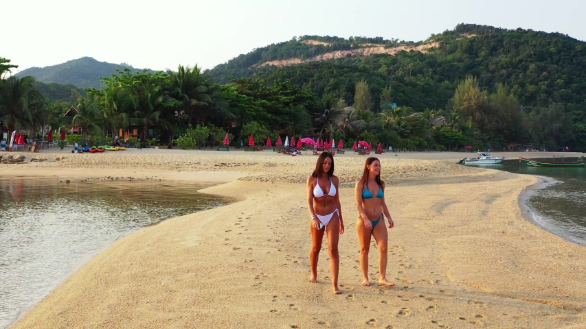 Young women in bikini exploring beautiful sandy beach stripe washed by calm clear water of sea lagoon in Jamaica