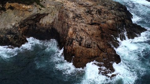 View of big waves breaking on the rocks of a little Island with percebes in a cloudy day. Finisterre.Spain. Drone Video