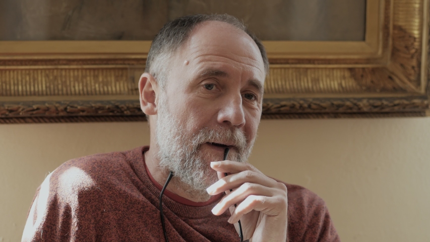 An elderly man rests looking at art objects while sitting on a bench in a Museum