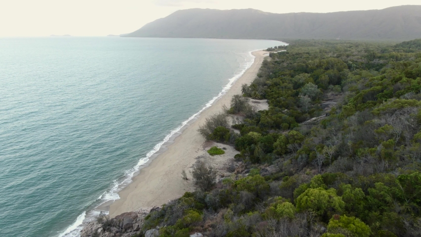 Cairns roadside beach DRONE aerial view. Turquoise ocean sea, white sand, road trip. Dramatic view from above. Travel, driving, road trip, holiday, vacation, paradise. Shot in Queenstown, Australia.