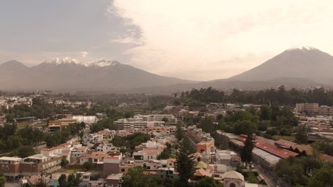 Beautiful Misti Mountain, with Arequipa city town buildings in foreground. DRONE aerial view. View of snow capped mountains in background at sunset. Shot in Peru.