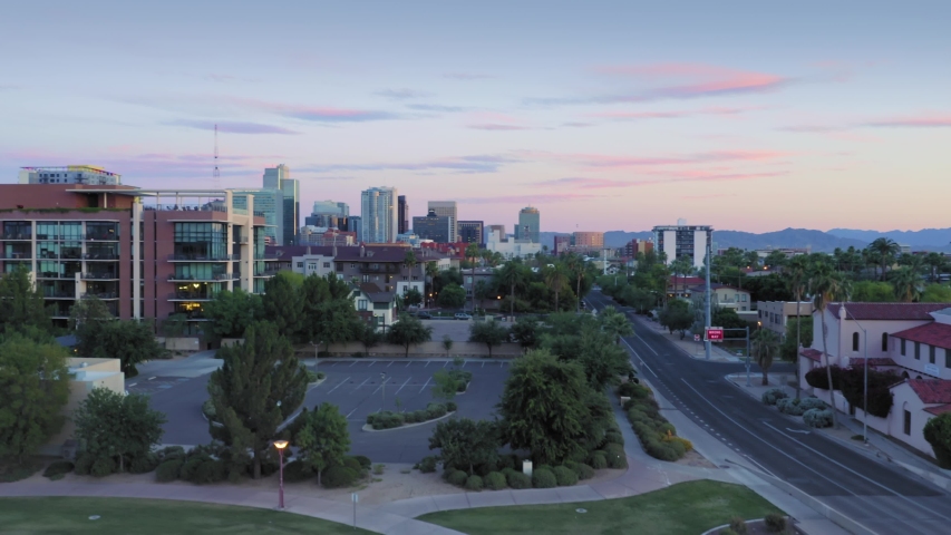 Aerial flying over suburbs & downtown Phoenix city skyline at sunset. Arizona, USA. 