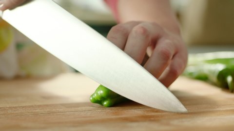 hands chopping green fresh pepper on a cutting board then throws peppers with a knife. Fast.