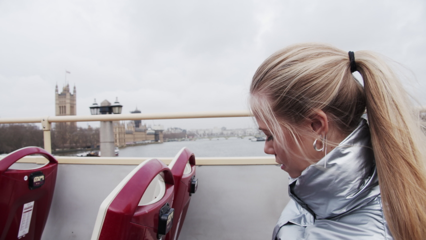 Medium Handheld Shot In Real Time Of Blond Teenage Girl Filming From Tour Bus With Smartphone Over London