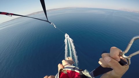 Amazing parasailing over Adriatic sea Croatia. First person view of parachute slings and bar with carabiners high above crystal blue water and motorboat