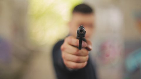 A man in a black suit aims his gun and shoots a gun.