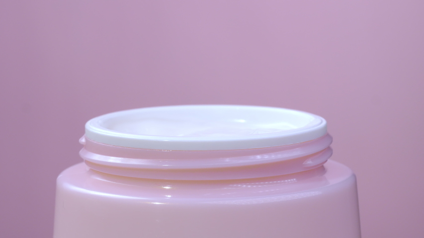A woman takes a white hand cream from a pink jar with her finger. The concept of beauty and health and skin care for the body, face and legs. Macro. Close up | Shutterstock HD Video #1050607939