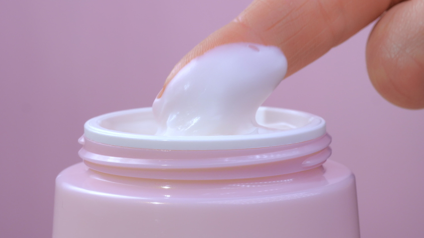 A woman takes a white hand cream from a pink jar with her finger. The concept of beauty and health and skin care for the body, face and legs. Macro. Close up | Shutterstock HD Video #1050607939