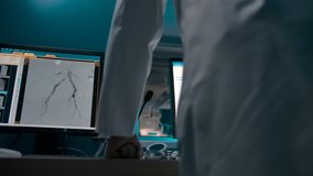 A dark-skinned African-American therapist watches the operation from a checkpoint. Monitors with X-rays and patient data in front of a professional surgeon. - Powered by Shutterstock - Get 15% off with code: PIKWIZARD15