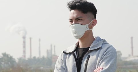 back view of asian man look something and wears protective n95 mask against air pollution in front of factory