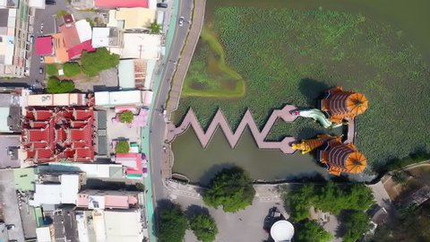 Top down Hyper-lapse of people walking on a zigzag Bridge toward Dragon & Tiger Pagoda & cars driving on the highway by Lianchihtan Lotus Lake, a famous tourist attraction in Zuoying, Kaohsiung Taiwan
