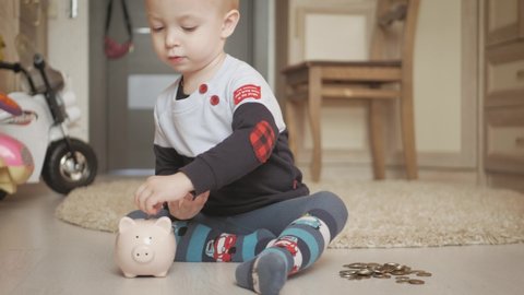 Little boy putting coins into piggy bank for the future savings at home.