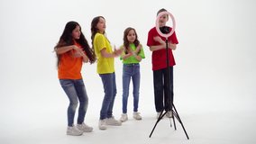 Three teen girls and a boy smiling and shoots a video. Selfies. The phone is mounted on a tripod and the ring lamp shines - Powered by Shutterstock - Get 15% off with code: PIKWIZARD15