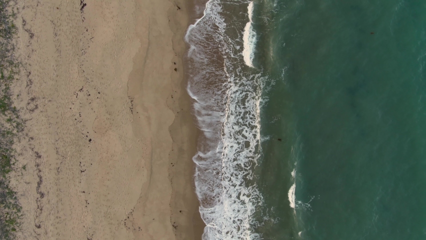 Cairns beach DRONE aerial view. Turquoise ocean sea, white sand, road trip. Dramatic birdseye view from above beach coast. Travel, sun, holiday, vacation, paradise. Shot in Queenstown, Australia.