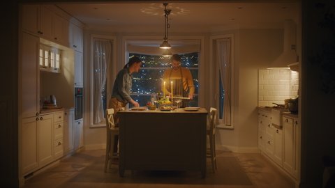 Happy Couple Cooking and Having Dinner Together. They Prepare Food, Serve Table. Lovely Boyfriend and Girlfriend Have Romantic Evening with Wine, Festive Table in Stylish Cozy Kitchen Interior