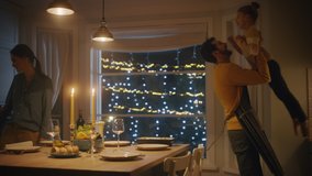 Happy Family of Three Cooking and Having Dinner Together. Mother Prepares Food, Cute Little Girl Runs to Father, Hugs Him and They Dance. Festive Table in Cozy Kitchen Interior. Slow motion - Powered by Shutterstock - Get 15% off with code: PIKWIZARD15