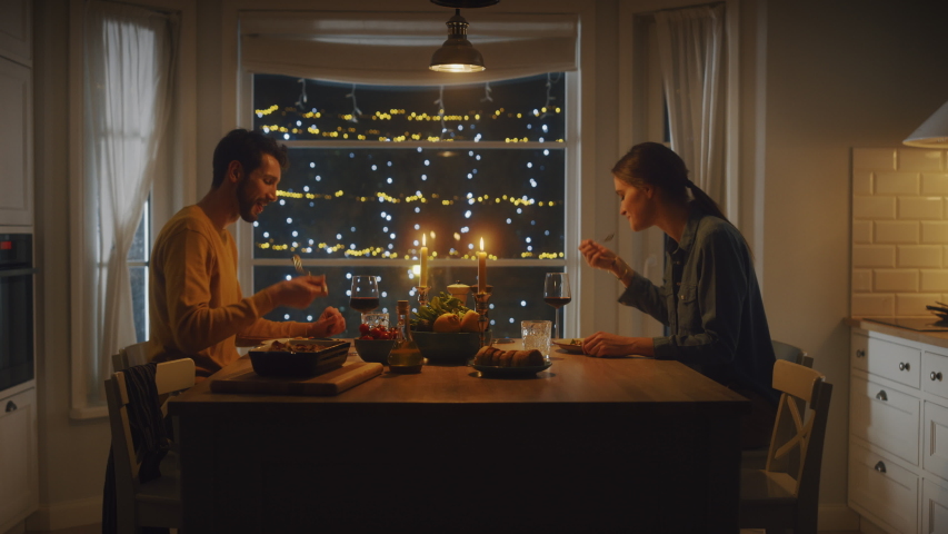 Happy Young Couple in Love Have Romantic Dinner, Toasting Each other with Glasses of Wine, Eating Tasty Meal in the Kitchen, Celebrating and Talking. Lovely Husband and Wife Have Romantic Time | Shutterstock HD Video #1050644728