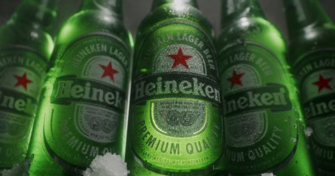 MINSK, BELARUS - 04.10.2020: zoom sliding epic video of five Heineken cold beer bottles in steam, macro wide shot of heineken beer thawed beer bottles in water drops, packshot tabletop in 4k Prores