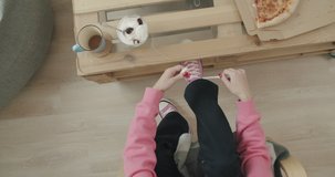 Young woman skateboarder tying shoelace in pink sneakers. Close-up of legs of girl sitting on chair at home and getting ready for walking. Top view 4k raw video footage slow motion