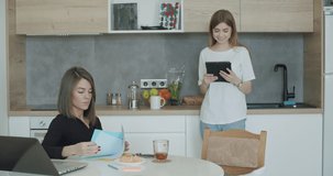 Young people have breakfast at home. Caucasian woman drinking coffee using tablet chatting in social net or surfing internet reading news. Modern family working at home. 4k video footage slow motion