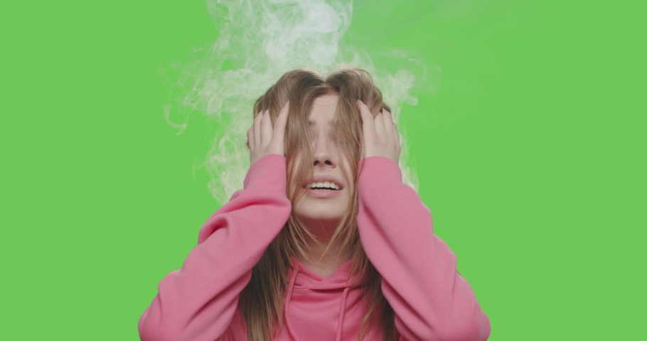 Young woman shooting gesture on green screen. Close-up of tired girl making sign gun by hand posing at chroma key background. Smoke coming out of head. 4k video footage slow motion