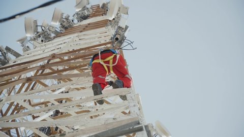 a technician climb the tower and move position. A tower technician with complete equipment move stakes from side to side 