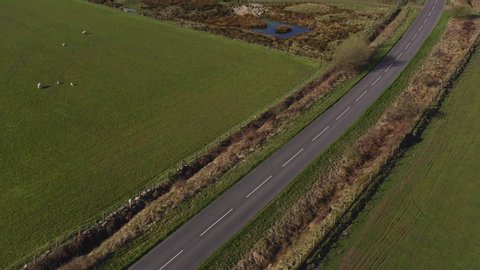 Drone footage of a person mountain biking along an empty country road on a sunny morning in North Yorkshire England completely isolated