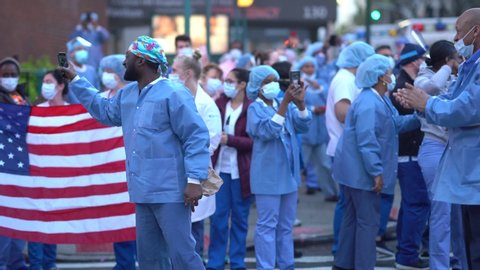 New York City, New York / USA - April 17 2020: New York hospital healthcare workers and nurses clapping expressing gratitude for saving lives during pandemic coronavirus outbreak in New York City. 