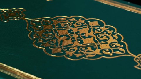 Lisbon, Portugal - April 8 Islamic Holy Book Koran's Cover Close Up Shot. Some Verses and Ornaments in Arabic Language. It Means 'God', 'God is Great'. Book on Turning Table. 4K Resolution UHD.