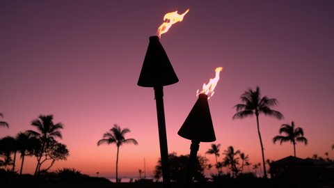 Hawaii sunset with fire torches. Hawaiian icon, lights burning at dusk at beach resort or restaurants for outdoor lighting and decoration, cozy atmosphere.