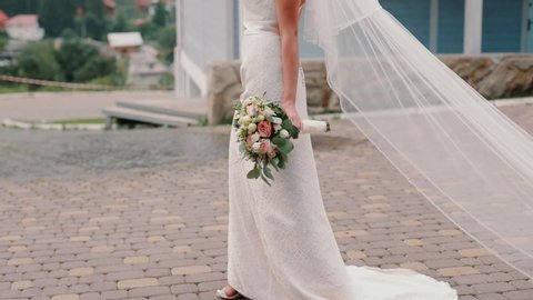 bride with a bouquet in a long dress that crawls on the ground – Stockvideo