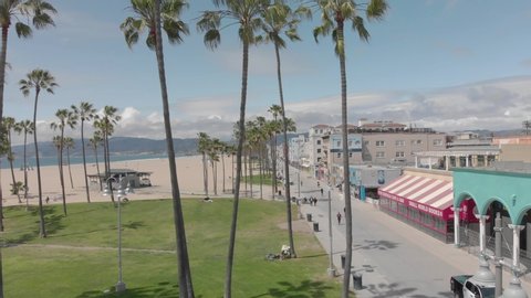 Los Angeles, CA/USA - April 8, 2020: People walk, bike, and run on the Venice Beach boardwalk while social distancing during the coronavirus stay-at-home order aka lockdown. Normally full of tourists.