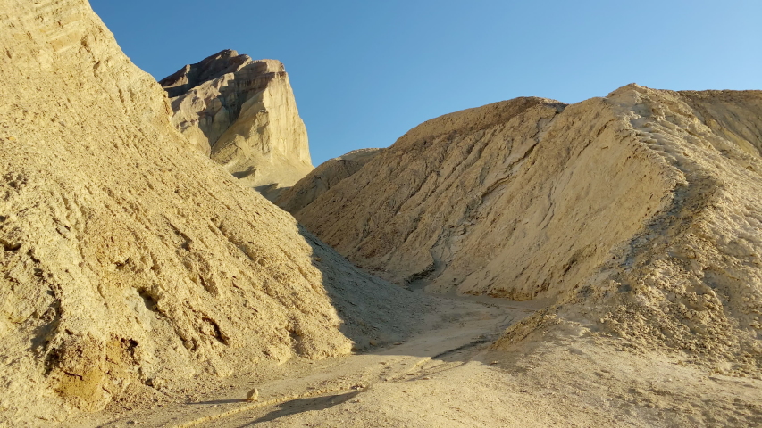Manly Beacon visible in the distance beyond the canyon walls of Golden Canyon at Death Valley National Park, California. Slide left to right.