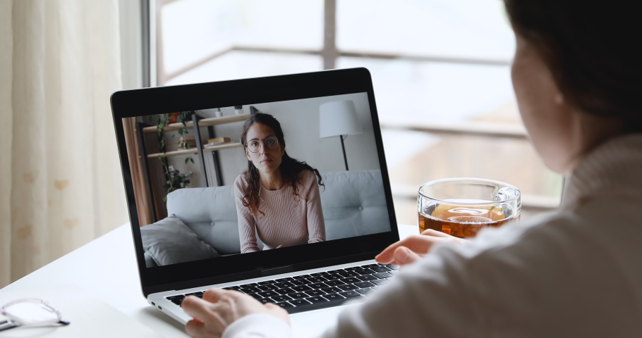 Young woman student elearning with distance teacher talking with online psychologist during webcam counseling consultation, watching training, making video call. Over shoulder laptop screen view. Royalty-Free Stock Footage #1050675400