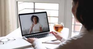 Young caucasian woman student, remote worker talking with african online teacher, psychologist, friend by webcam video call in virtual conference app concept. Over shoulder laptop screen closeup view