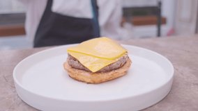 Golden Burger with cheese.cheese melted on the bun with the meat.Cook using blow torch to melt cheese on meat cutlet of burger. Slow motion food video.