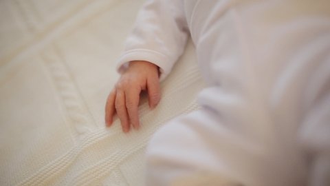 The adorable newborn baby sleeping in crib. Close up of little baby hand and tiny fingers. Baby in suit clothes