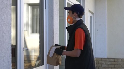 Social distancing and self-isolation. Coronavirus pandemic. Latino American courier in protective mask and gloves. Contactless delivery of take-away food from the restaurant