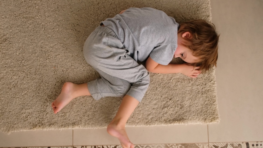 Sad little boy lying on the floor at home at the day time | Shutterstock HD Video #1050698506