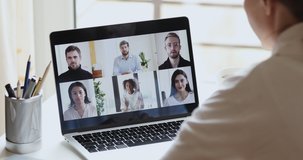 Diverse business people group conferencing in online chat on laptop screen. Over shoulder view of female remote worker video calling working from home office. Team virtual meeting by web cam concept