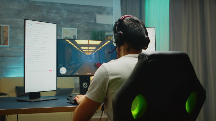 Back view of professional gamer streaming his competition on triple monitor setup with two streaming chats open | Shutterstock HD Video #1050709393