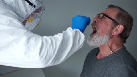 Coronovirus test family risk group. Doctor in a protective suit takes a swab from the throat from an elderly woman pensioner then from her husband. Non-invasive diagnostic method by PCR reaction