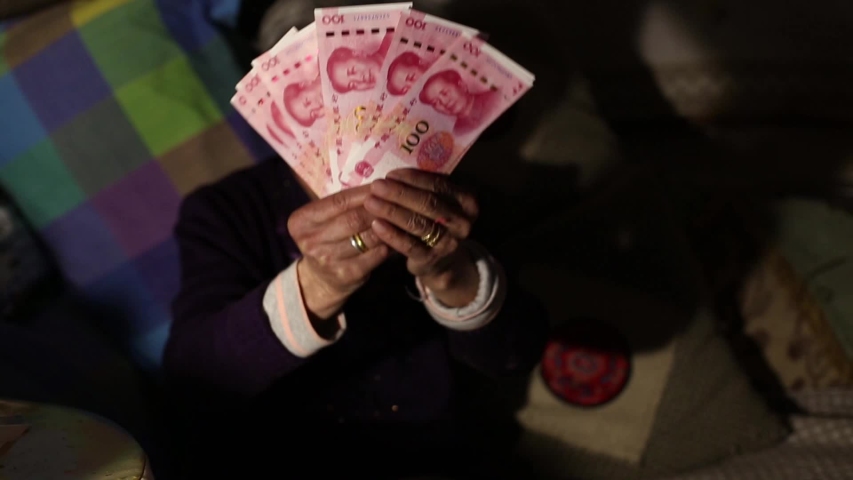 Elderly woman showing pension - Chinese Yuan banknotes at home, Beijing, China