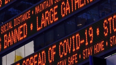 Closeup view of a Times Square ticker says stay safe and say home and large gatherings are banned. Physical distancing was a common practice to slow the spread of COVID-19 during the pandemic of 2020.