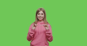 Attractive young woman cleans glass reusable straw with a brush over chroma key green screen background. 4k raw footage smow motion