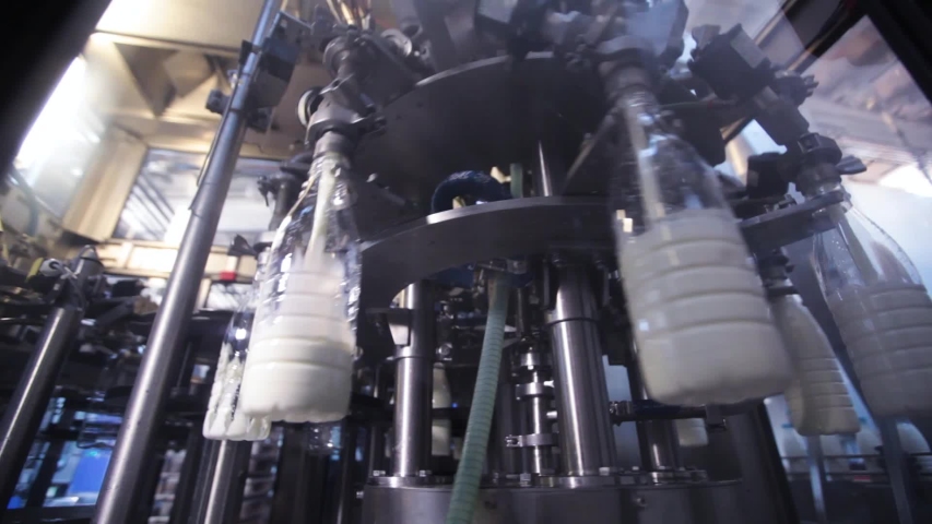 Milk production at factory.White plastic bottles transported on conveyor. Modern equipment.