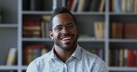 Close up head shot pleasant young mixed race man in glasses looking at camera, starting smiling laughing at funny joke. Confident handsome millennial businessman worker leader posing for portrait.