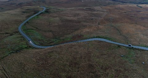 Aerial view of Kerry Road in Ireland. Vast, dry landscape. Cars driving on road.