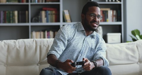 Addicted to technology young african american hipster man holding , playing online console car racing shooting videogame alone at home, feeling dissatisfied with losing round, hobby concept.