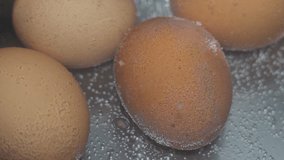 Chicken eggs are boiled in a pan in water on a gas stove close up